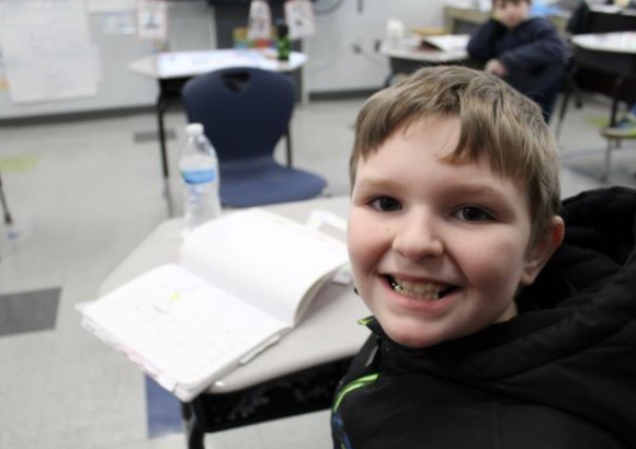 Student smiling at his desk 